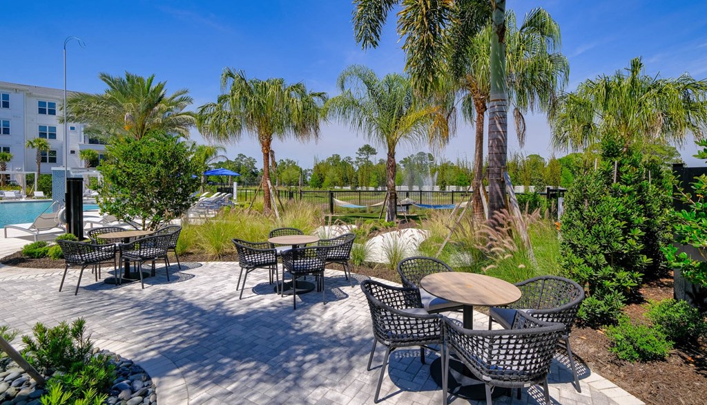 a patio with tables and chairs and palm trees