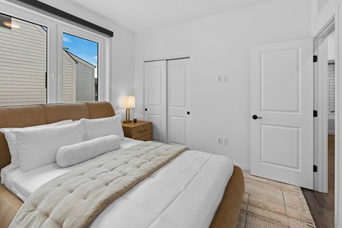 2 Bedroom Townhomes in Bozeman, MT - Highmark Bozeman - Bedroom With Luxury Wood-look Plank Flooring, Area Rug, Bed, Nightstand With Lamp, Closet, And Large Window.