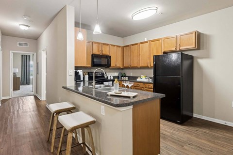 A kitchen with wooden cabinets and a black refrigerator.