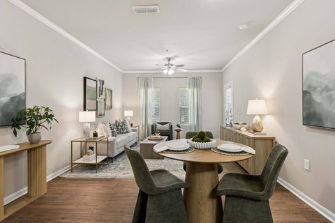 A dining room with a table set for two and a couch in the background.