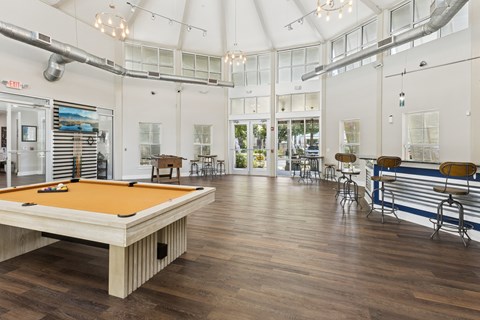 A pool table is in the middle of a room with a bar and a pool table.
