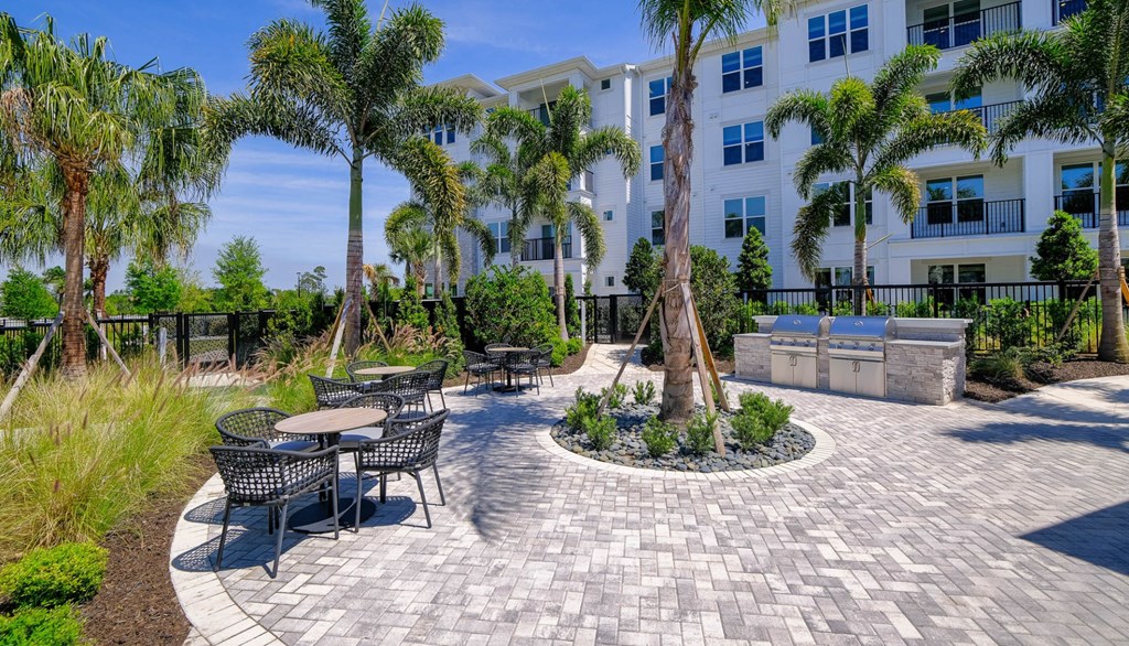 a patio with tables and chairs and palm trees