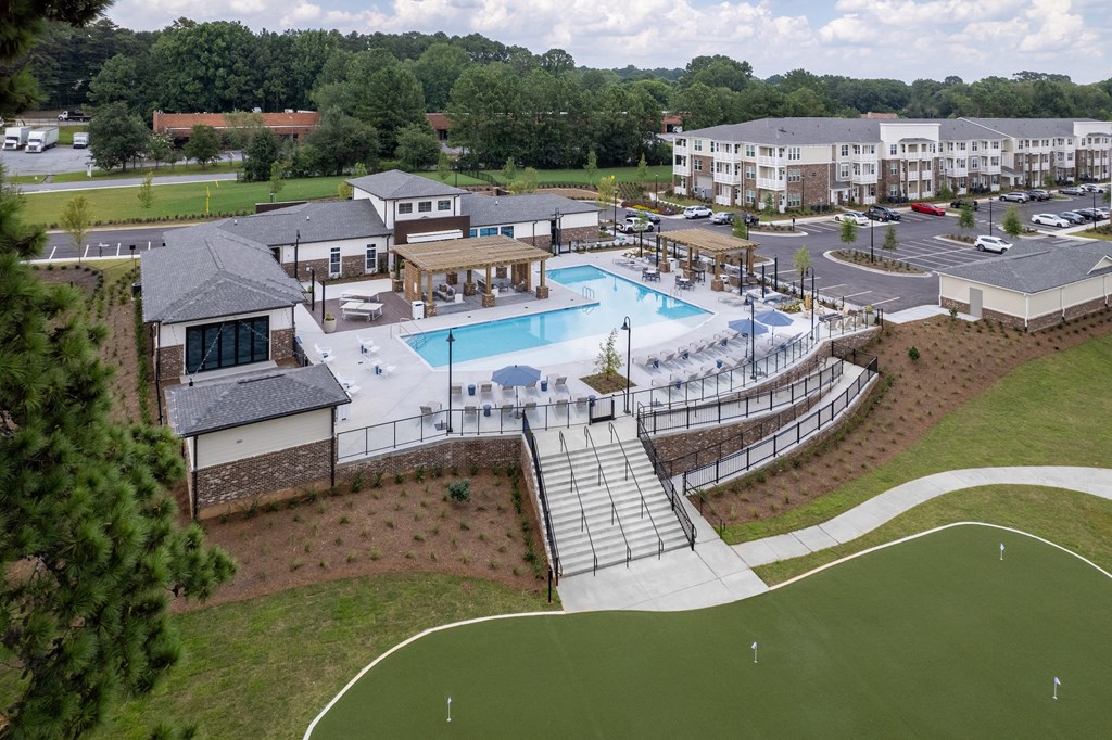 an aerial view of a resort style pool with a clubhouse in the background