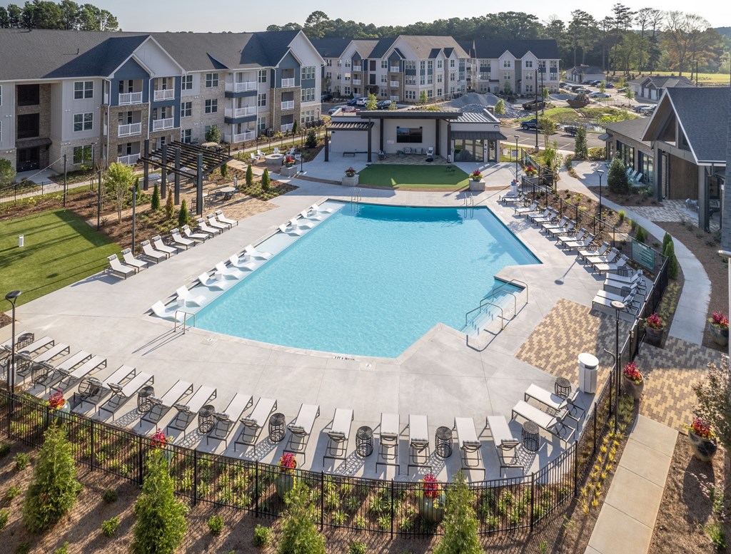 an aerial view of a resort style pool with chaise lounge chairs and a clubhouse in the