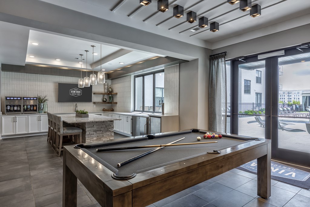 a pool table in a clubhouse with a kitchen and a bar
