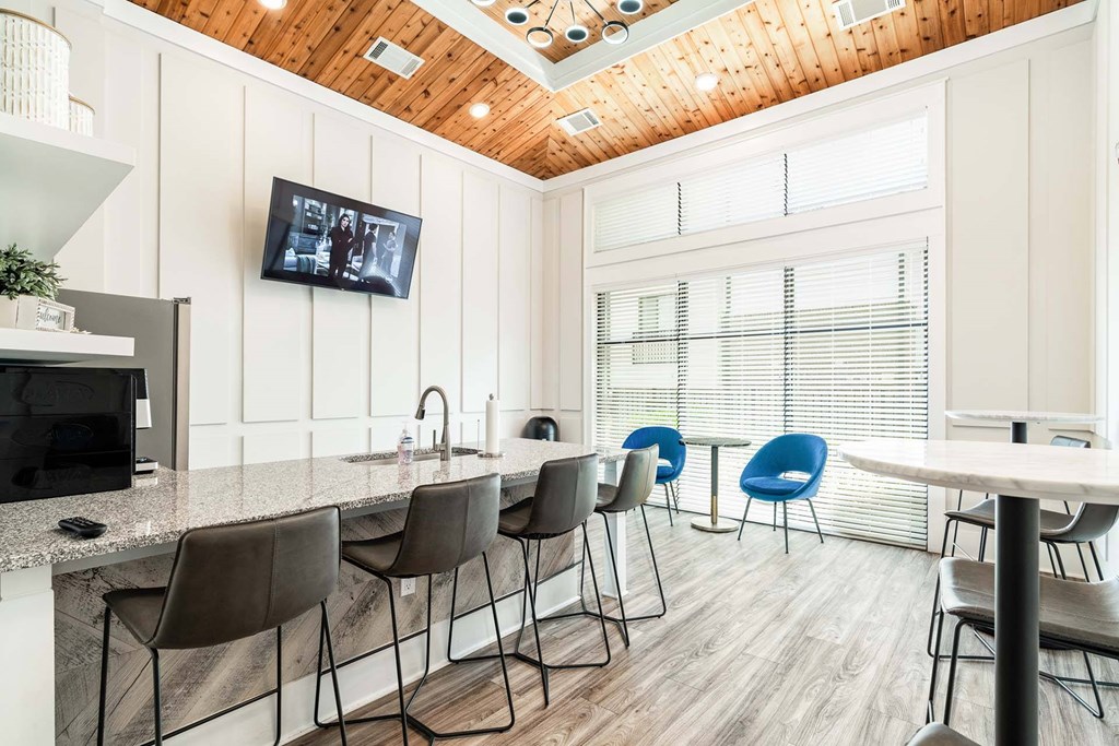 A modern kitchen with a bar area and a television mounted on the wall.
