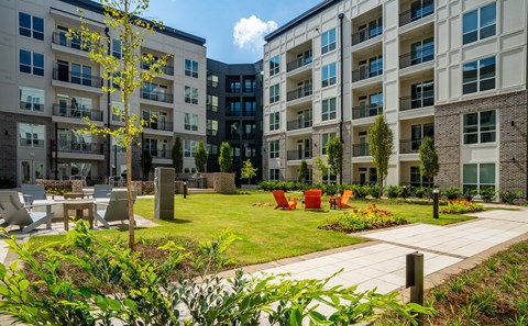 an outdoor area with chairs and tables in front of an apartment building
