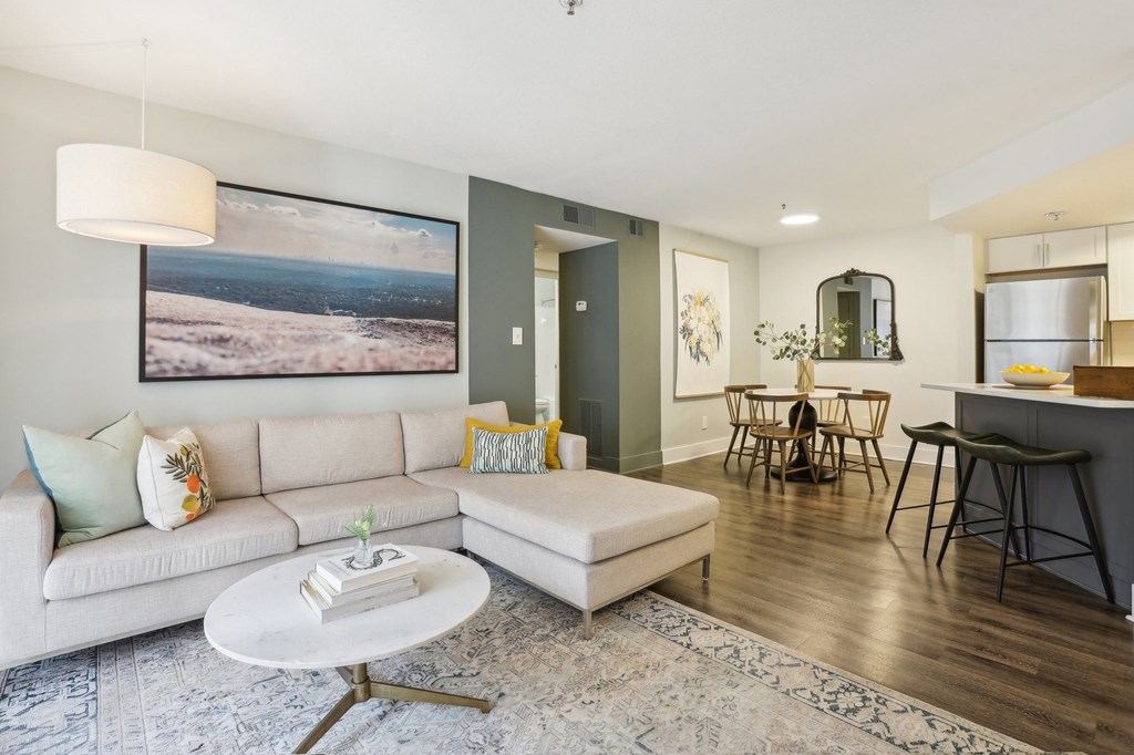 A living room with a white couch and a large landscape painting on the wall.