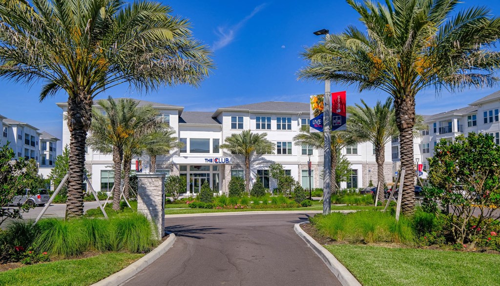 a building with palm trees and a road in front of it
