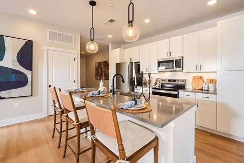 A kitchen with a table set for four with a painting on the wall.