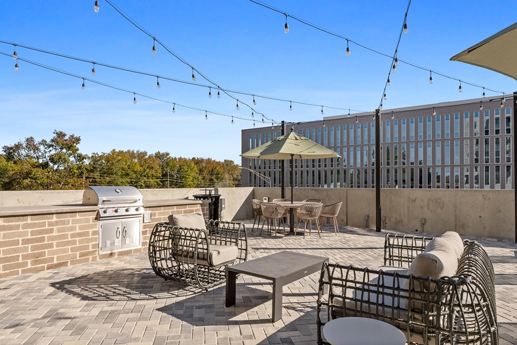 A patio with a table, chairs and a grill.