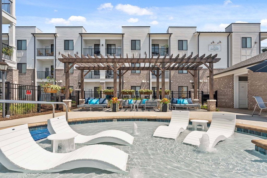 A pool area with a wooden pergola and lounge chairs.