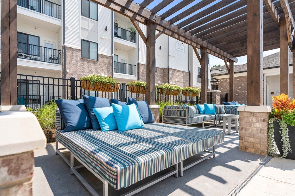 A patio with a striped cushion sofa and a wooden pergola.