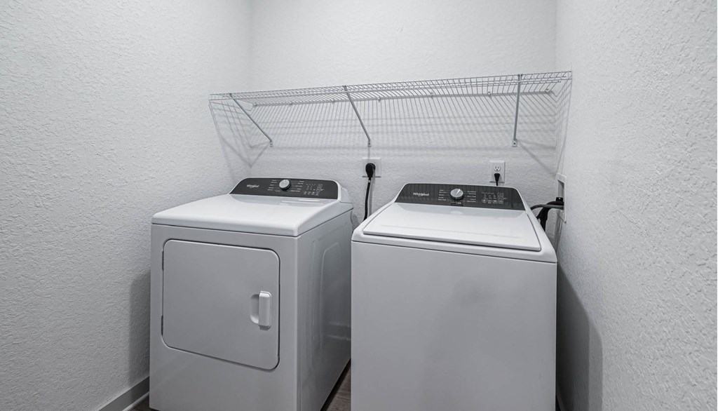 two washers and dryers in a laundry room with a rack on the wall