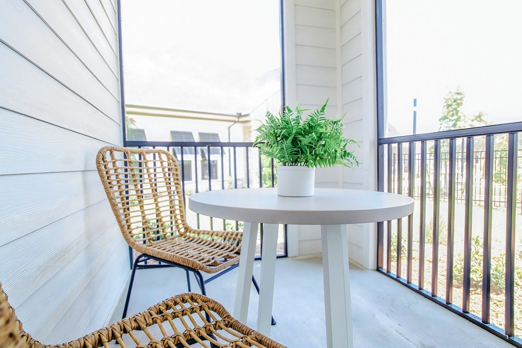 a balcony with a table and two chairs and a potted plant