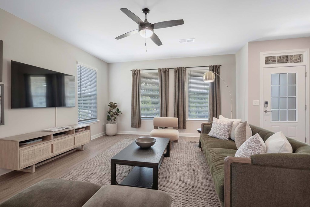 A living room with a brown couch, a coffee table, and a ceiling fan.