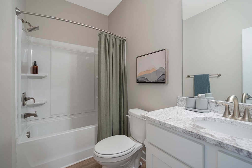 A white bathroom with a toilet, sink, and shower.