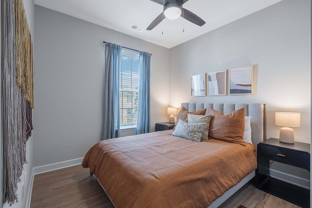 A bedroom with a bed, a ceiling fan, and a window with curtains.