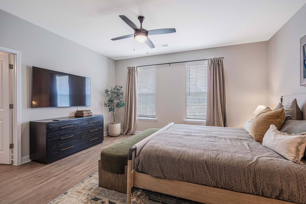 A bedroom with a bed, dresser, and ceiling fan.
