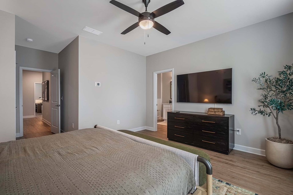 A bedroom with a bed, dresser, and ceiling fan.