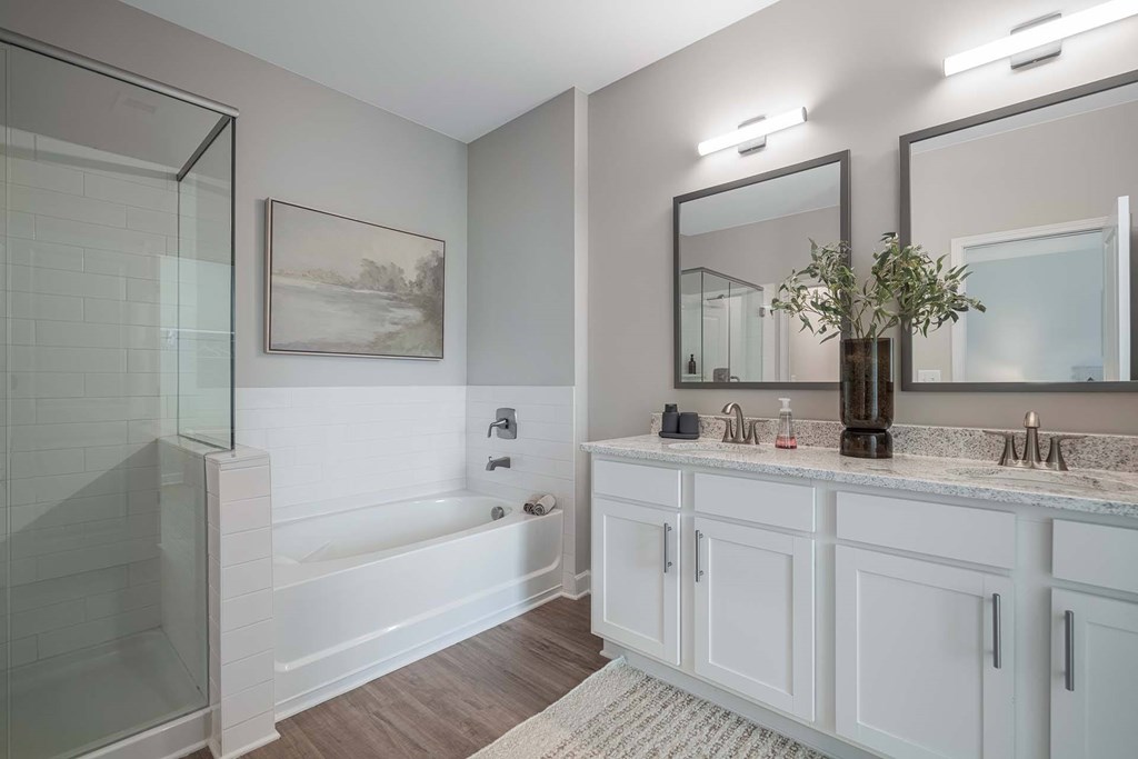 A bathroom with a white tub, sink, and mirror.