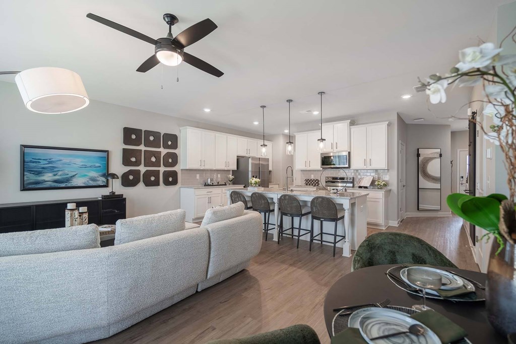 A modern living room with a grey sofa and a dining table set for four.