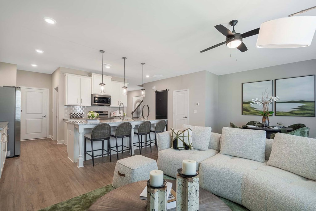 A modern living room with a dining area and kitchen in the background.