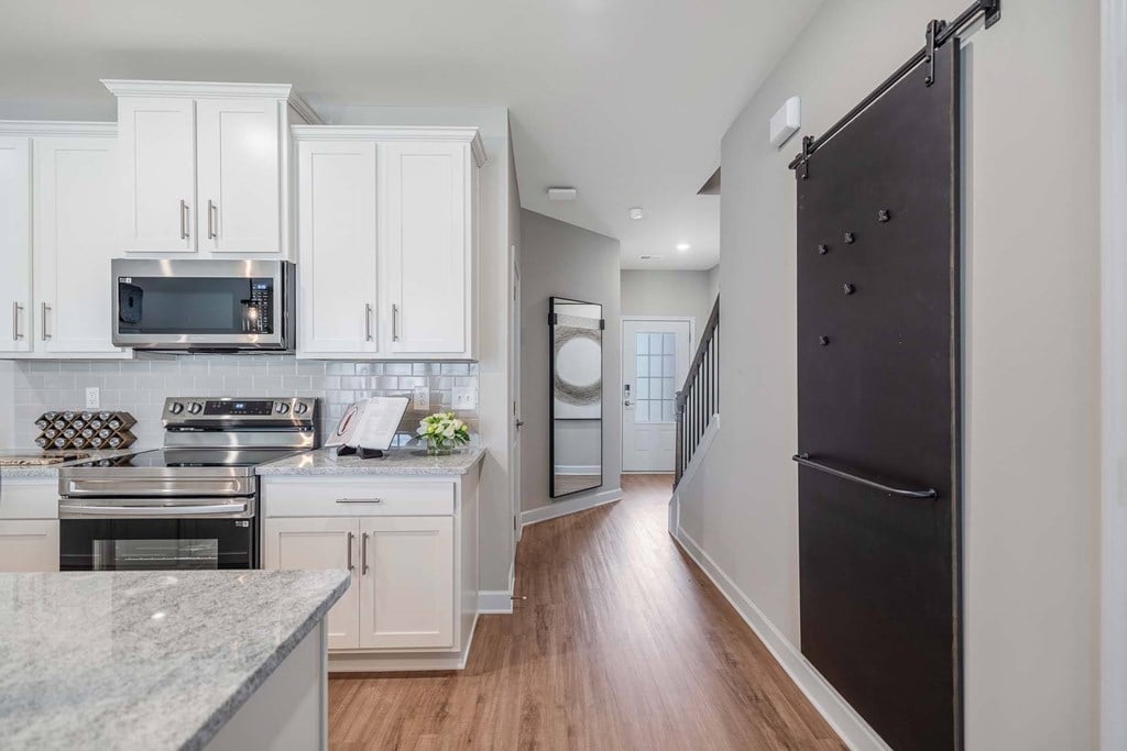 A kitchen with white cabinets and a black refrigerator.