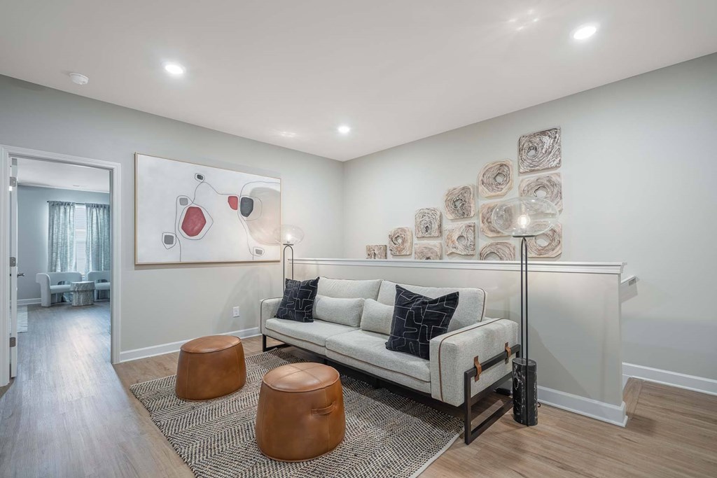 A living room with a white couch and a painting on the wall.