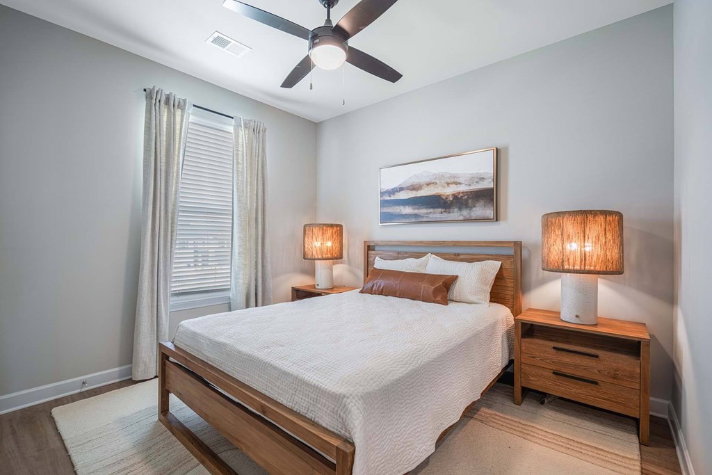 A bedroom with a bed, nightstands, and a ceiling fan.