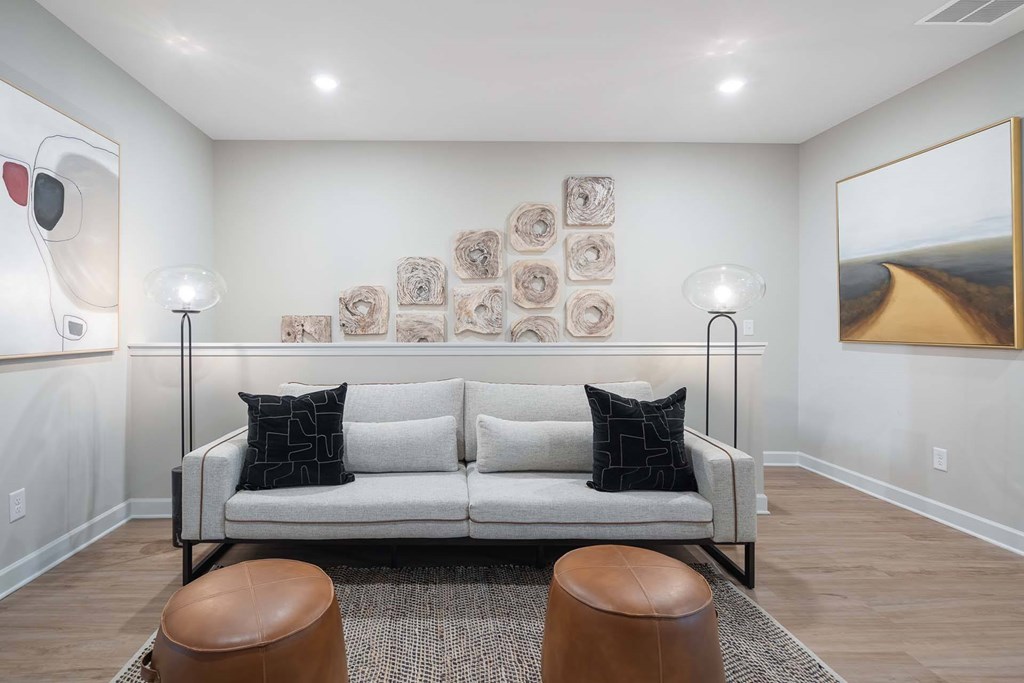 A living room with a white couch and a painting on the wall.