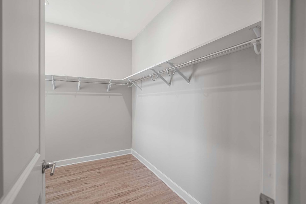 A white closet with a wooden floor and white walls.