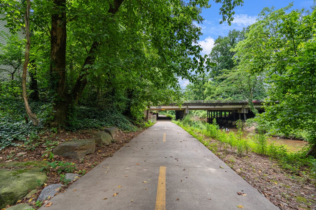 A pathway with a yellow line in the middle leads to a bridge over a river.