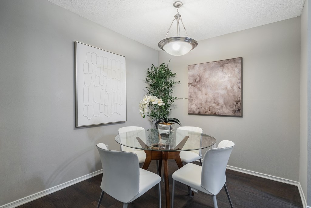 A dining room with a glass table and white chairs.