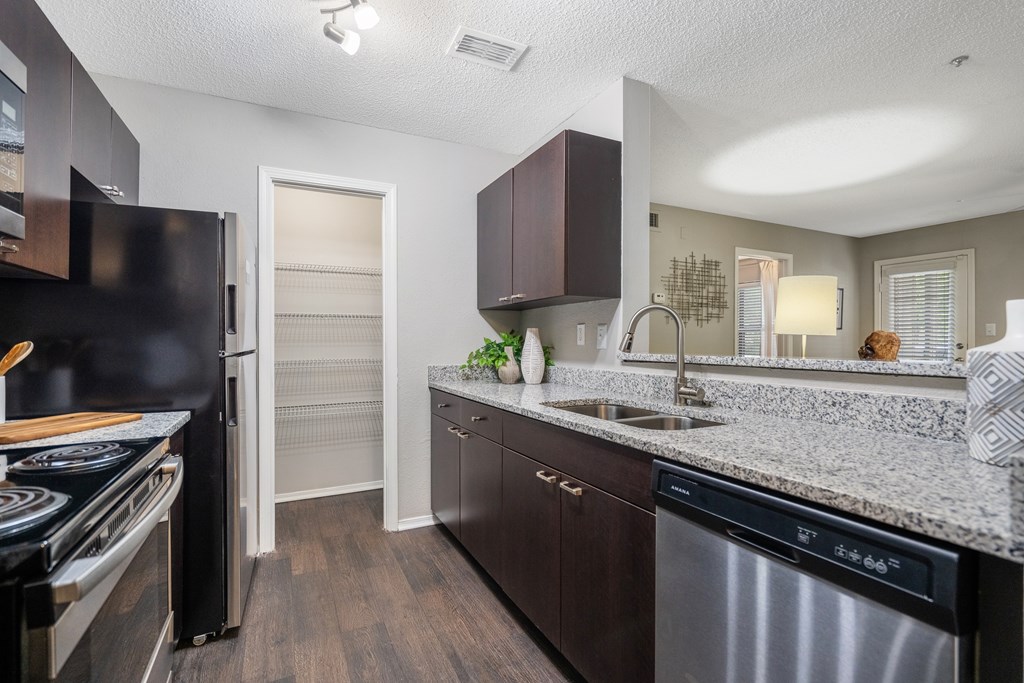 A kitchen with dark brown cabinets and a stainless steel dishwasher.