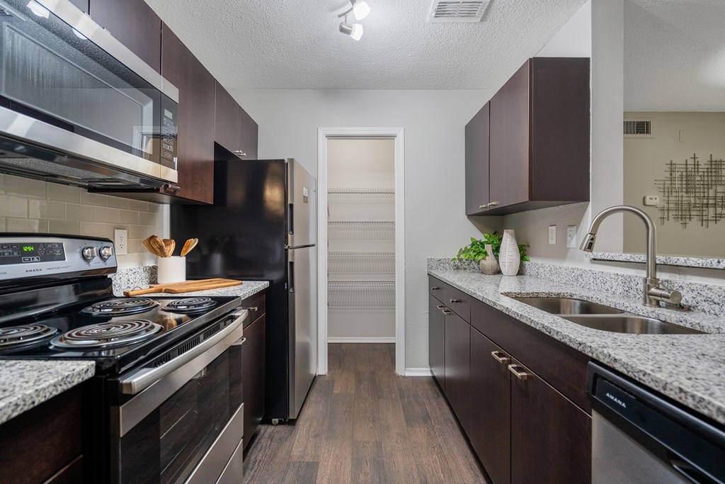 A kitchen with dark wood cabinets and a black stove top oven.