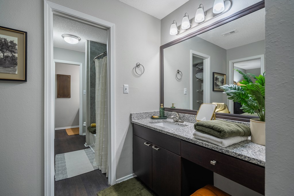 A bathroom with a vanity, mirror, and lights.