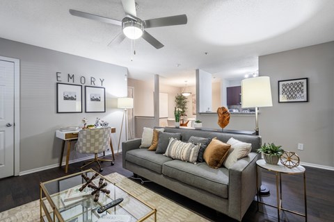 A living room with a grey couch and a glass coffee table.