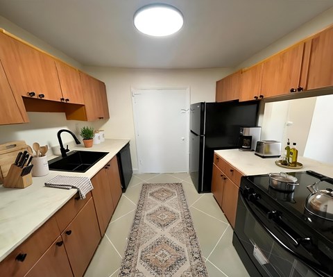A kitchen with wooden cabinets and a black fridge.