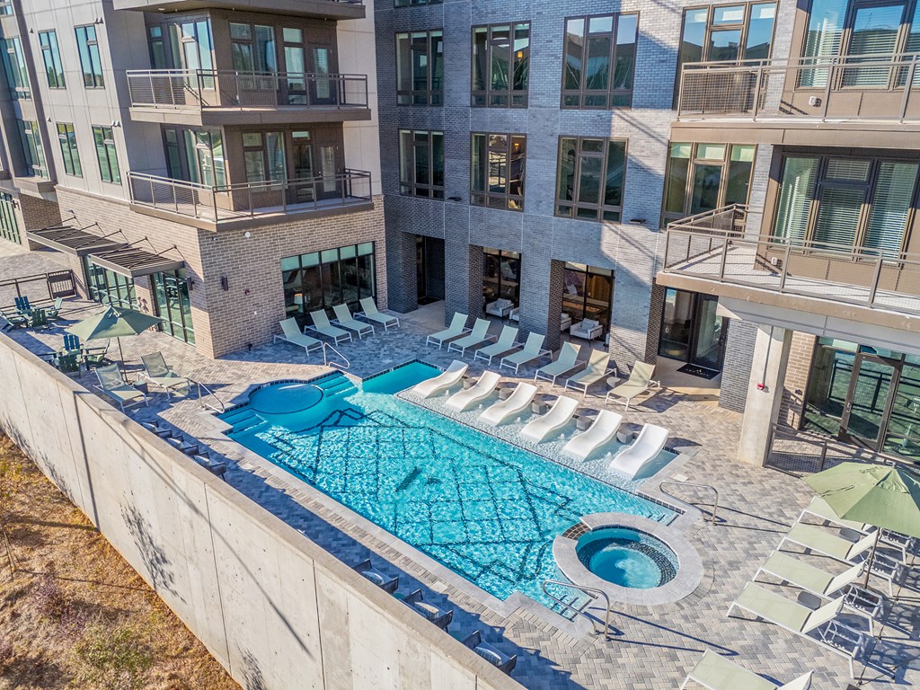 A large swimming pool surrounded by sun loungers and umbrellas.