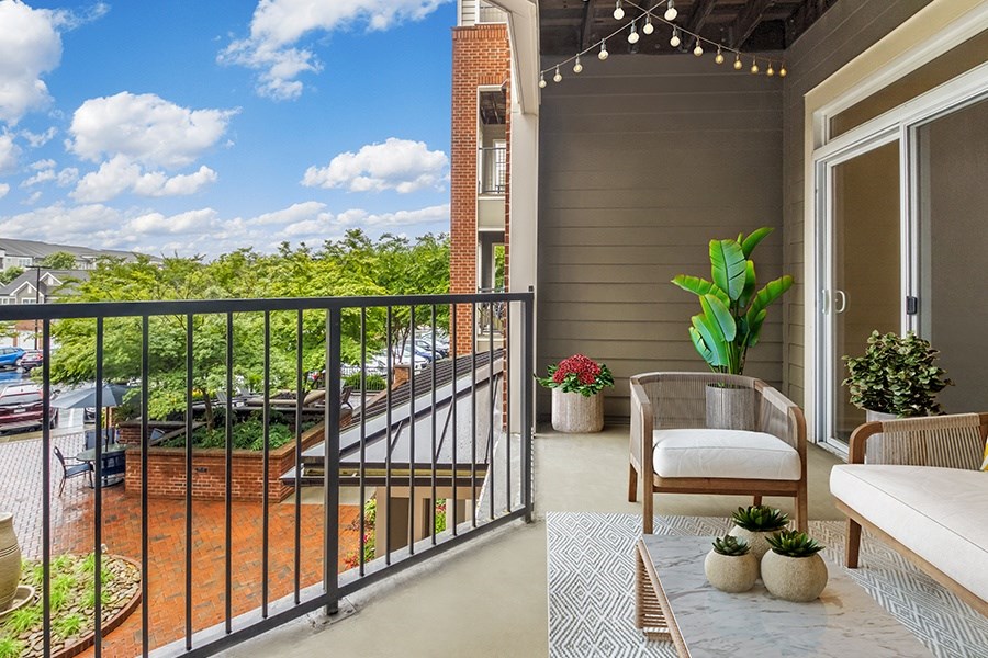 A balcony with a white couch, a chair, and a potted plant.