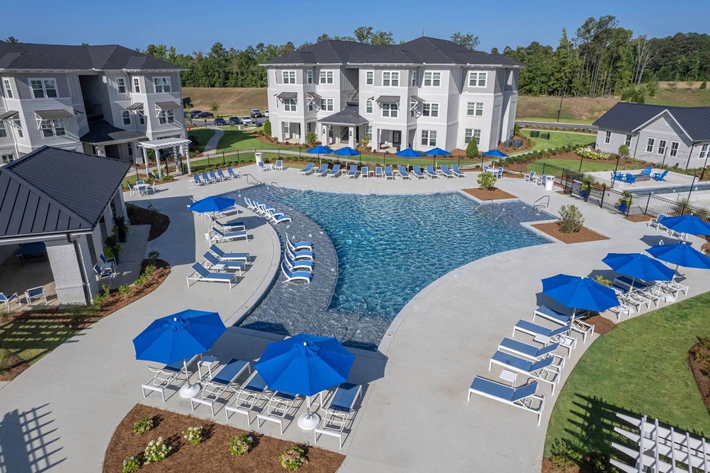 an aerial view of a swimming pool with lounge chairs and umbrellas in front