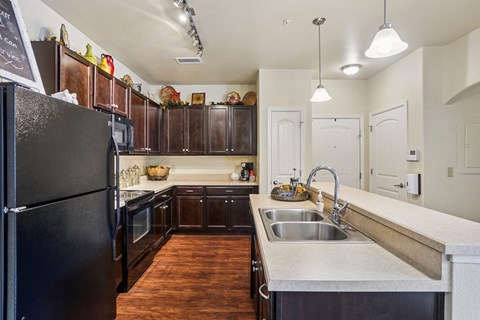 A kitchen with a black refrigerator and wooden cabinets.