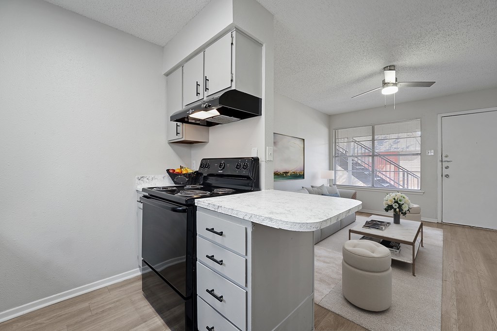 A modern kitchen with a black stove top oven and white countertop.