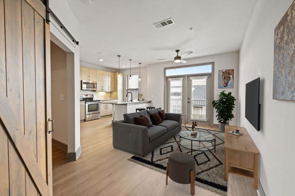 A modern living room with a grey couch and a glass coffee table.