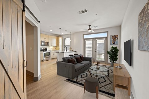 A modern living room with a grey couch and a glass coffee table.