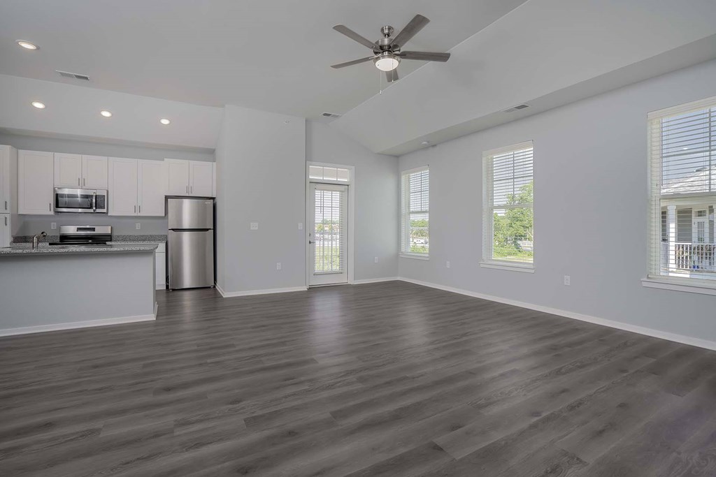Two Bedroom Luxury Apartments In Jeffersonville, IN - The Laurel - Kitchen with Stainless-Steel Energy Efficient Appliances, Granite Countertops, White Cabinets, and View of Unfurnished Living Area with Ceiling Fan.