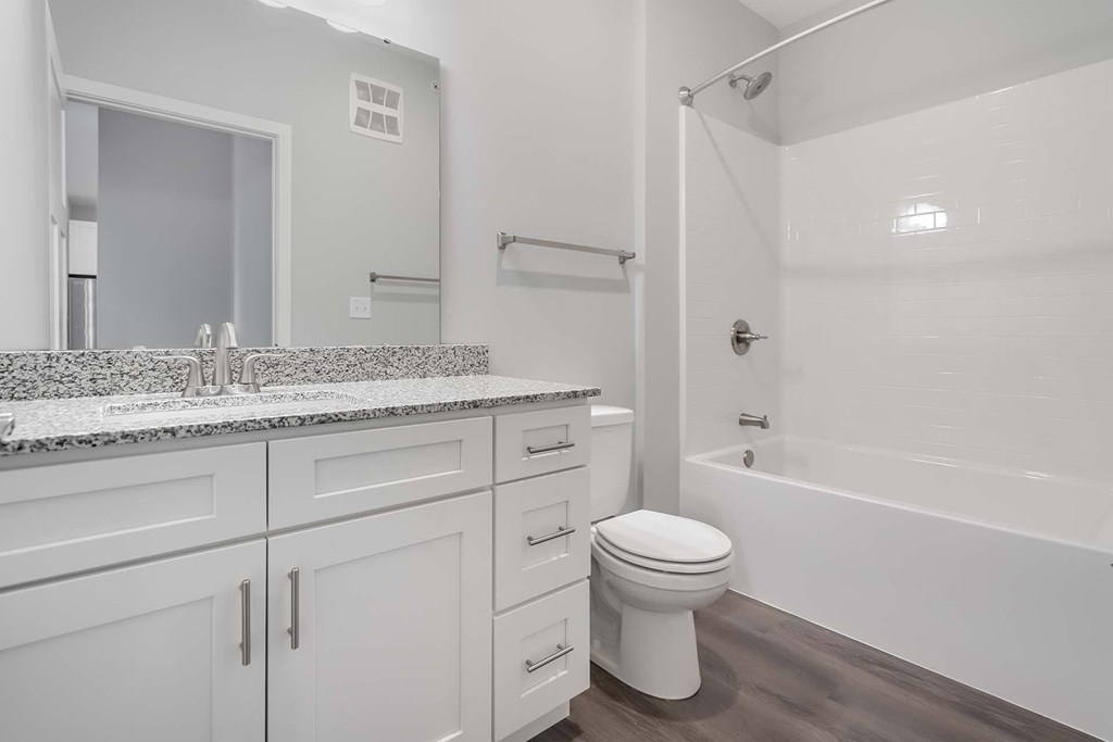 A white bathroom with a marble countertop and a white toilet.