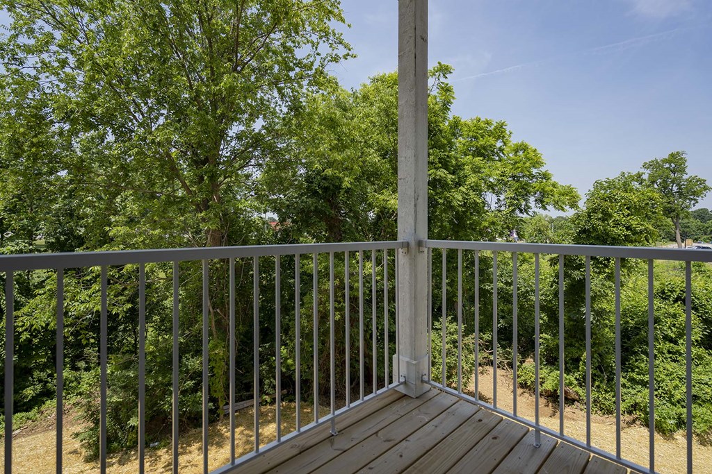 A deck with a metal railing and a tree in the background.