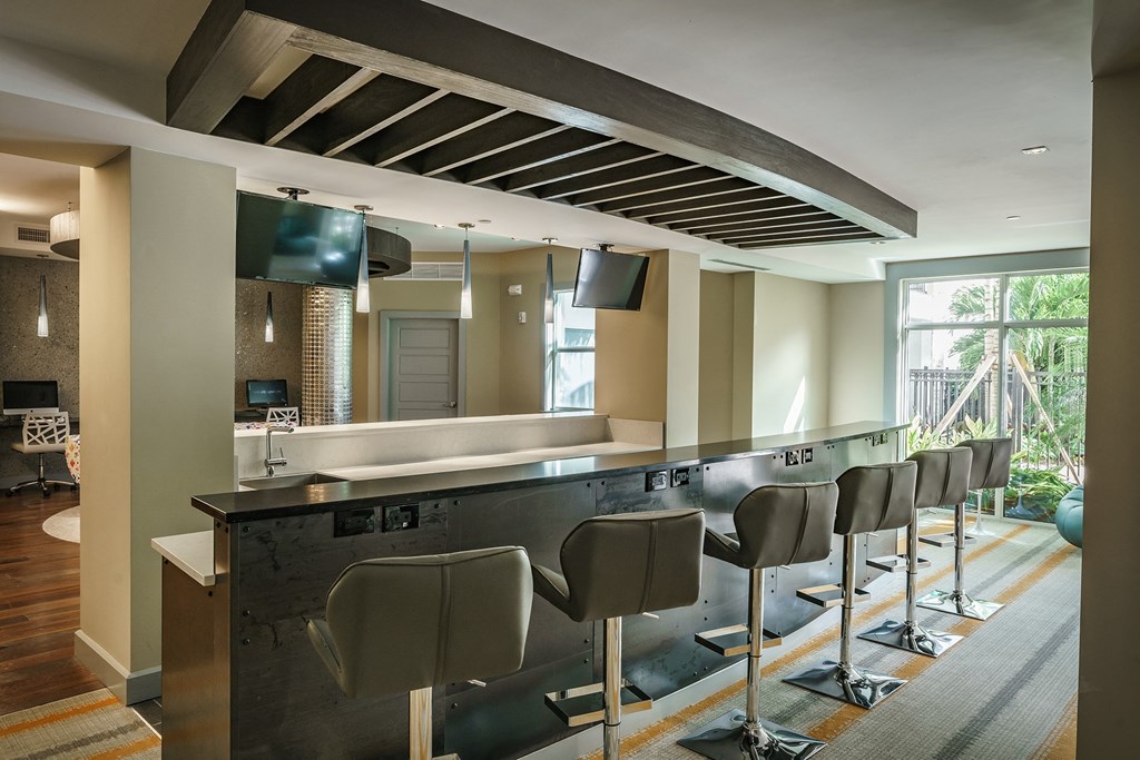 a kitchen with a bar and chairs in front of a window
